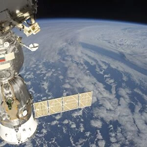 A docked Russian Soyuz spacecraft backdropped by Earth