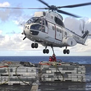 Sailors attach cargo legs to an SA330J Puma helicopter