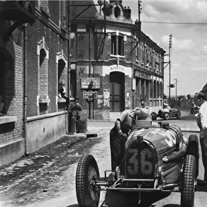 1932 French Grand Prix - Marcel Lehoux: Marcel Lehoux works on his Bugatti T54 after retiring, with the other competitors racing by behind