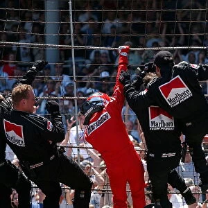 Spiderman Helio Castroneves (BRA) celebrates his back-to-back victory in his traditional manner on the catch fencing with members of the