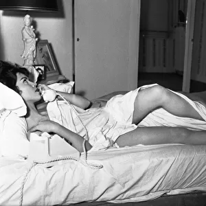 Actress Jackie Lane lying naked on the bed talking on the phone March 1959