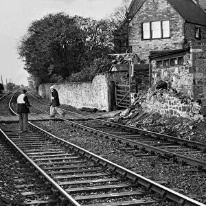 A British Rail workman escorts a pedestrian across the line after a wall crashes down