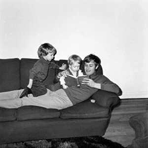 Families: Mother, father and children. Father reading a story to his baby boy on his sofa