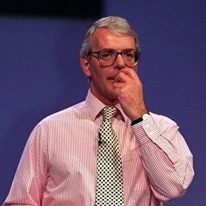John Major scratching his upper lip with left hand during speech at conference