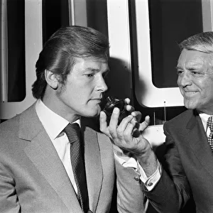 Roger Moore and Cary Grant sample one of their perfumes during their visit to their