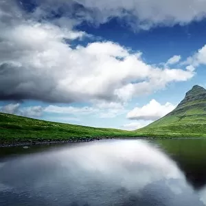 Picturesque landscape with Kirkjufell mountain, clear lake and cloudscape in blue sky