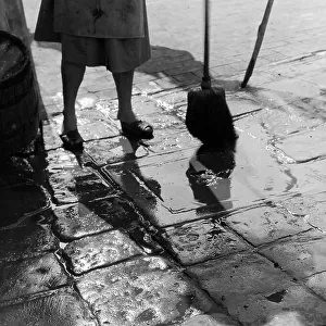"Overflow!" woman cleaning the pavement with a broom