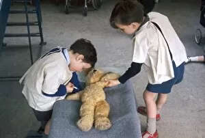 Two schoolboys give first aid to a teddy bear